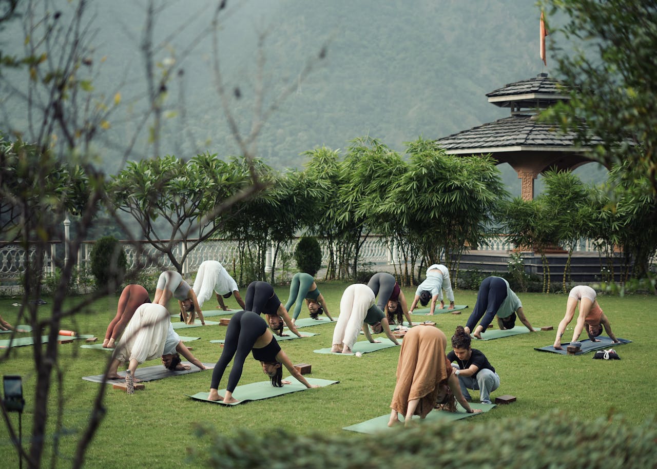 A group of adults practicing yoga outdoors at a Rishikesh ashram in India.