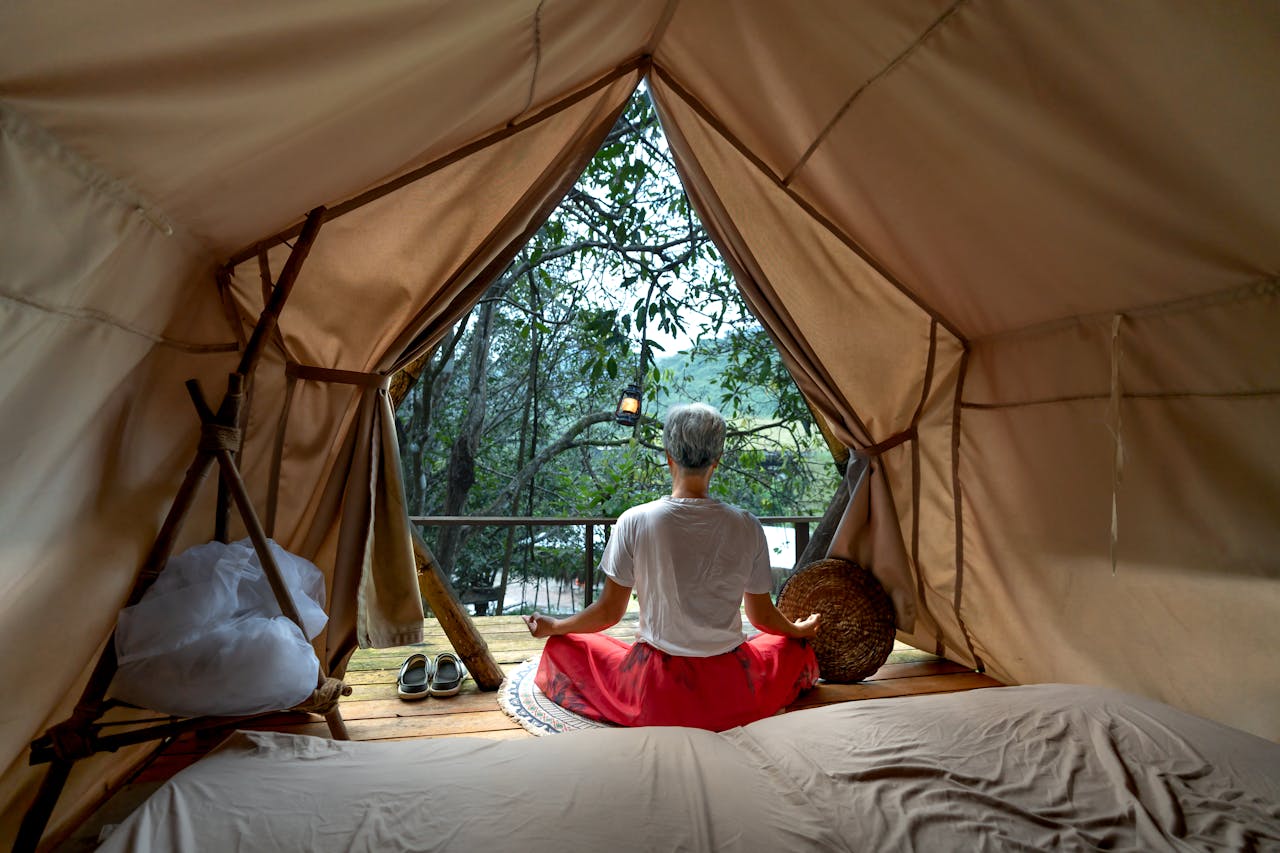 A woman meditates peacefully inside a tent, surrounded by natures tranquility.